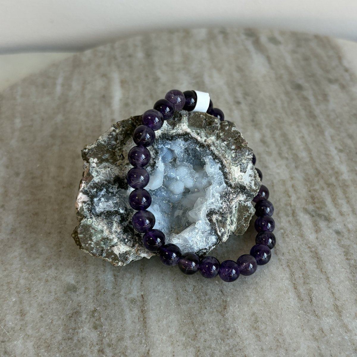Amethist kinderarmband rustend op een geode op marmer