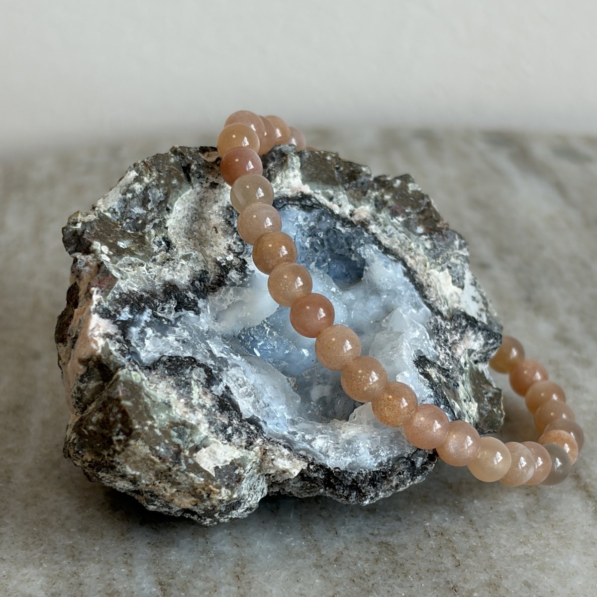 Perzik maansteen kinderarmband met warm roze 4 mm kralen op een geode