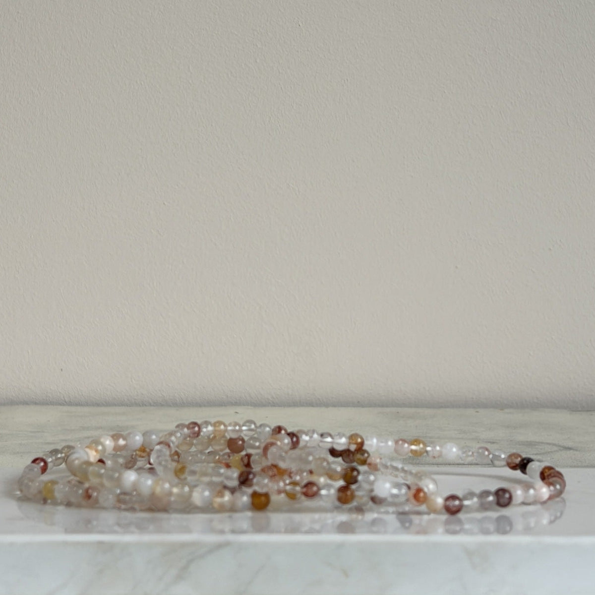 Hematoïde kwarts armband met transparante ronde kralen van 4 mm en roodbruine insluitingen.
