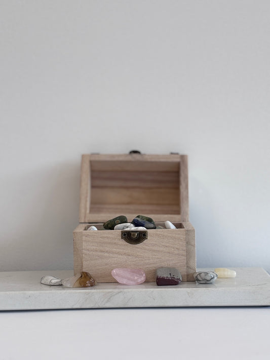 Houten schatkistje gevuld met kleine trommelsteentjes van verschillende edelstenen