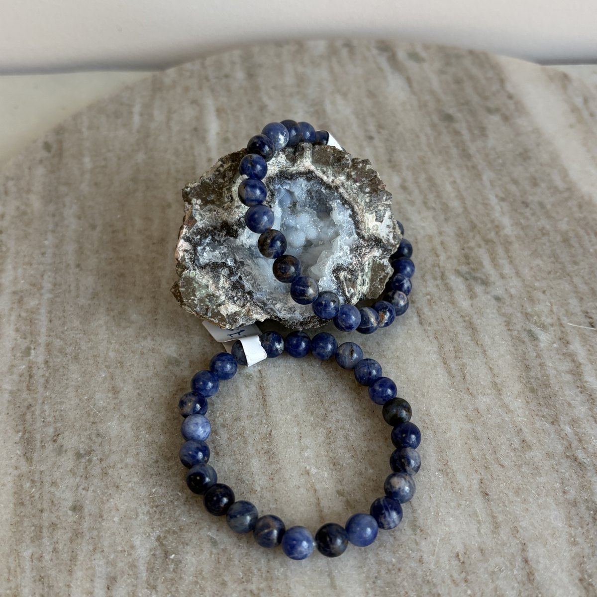 Sodaliet kinderarmband liggend voor een geode op marmer